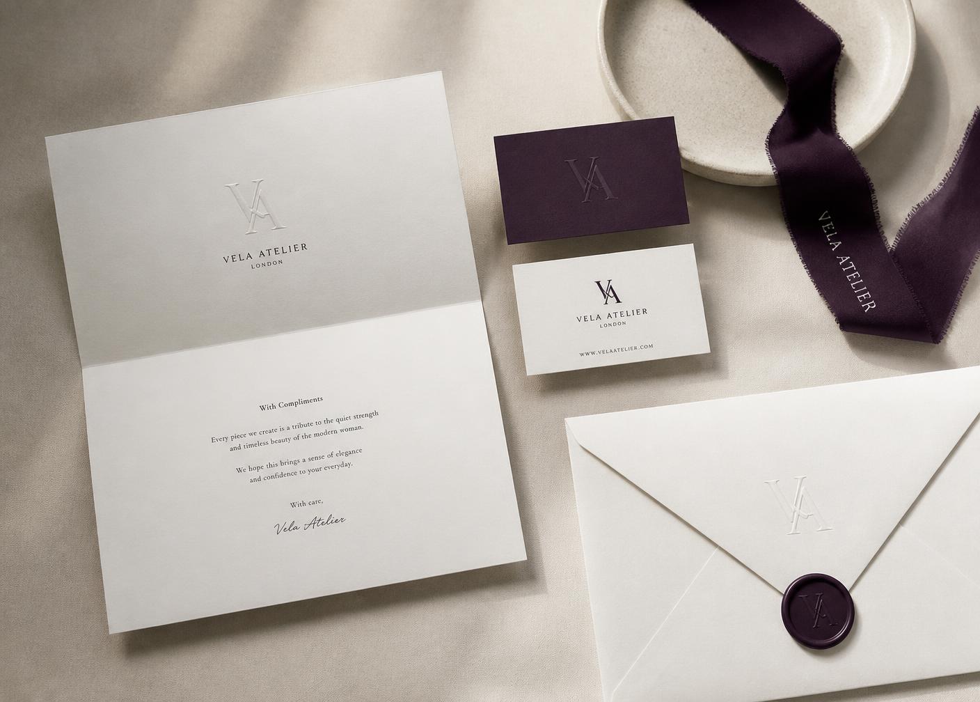 Brand identity stationery set with an embossed monogram on ivory paper and a deep violet business card